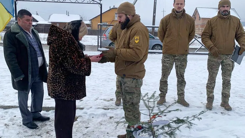 Військові вручають нагороду жінці на вулиці взимку