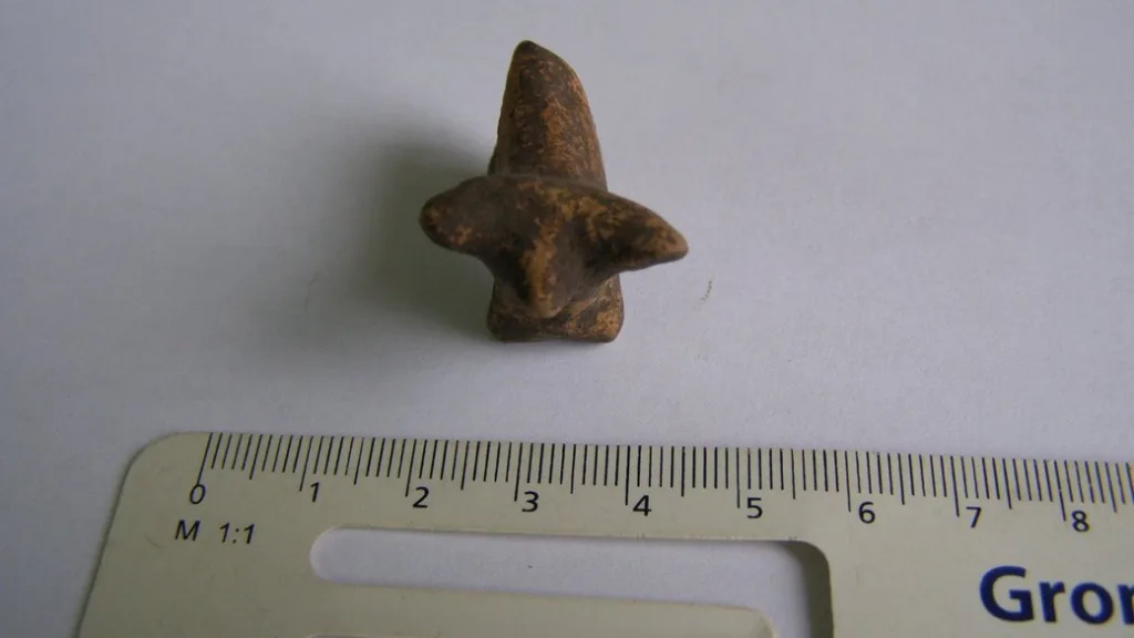 Маленька глиняна фігурка поруч з лінійкою