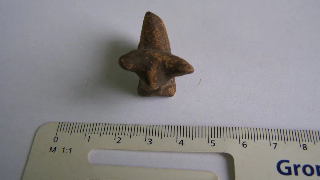 Маленька глиняна фігурка поруч з лінійкою