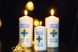 Запалені свічки Карітас України на темному тлі