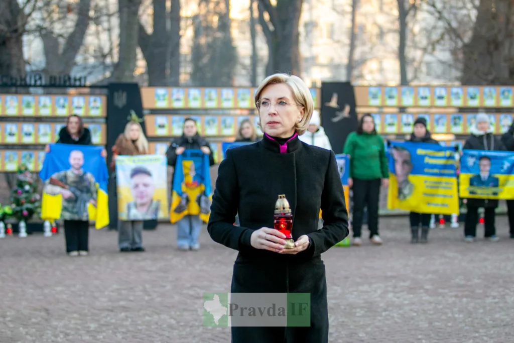 Жінка тримає лампадку на меморіальному заході