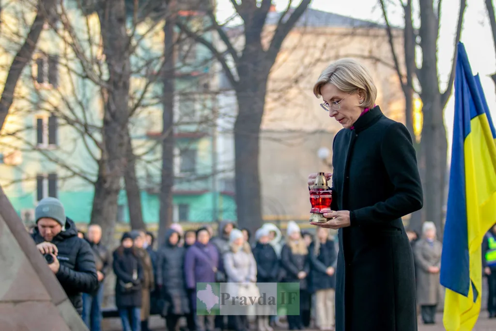 Жінка тримає лампадку біля українського прапора