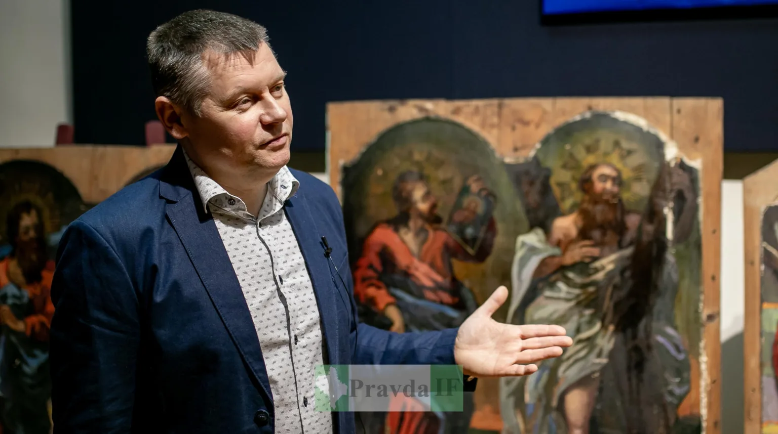 Чоловік розповідає поруч із релігійними картинами