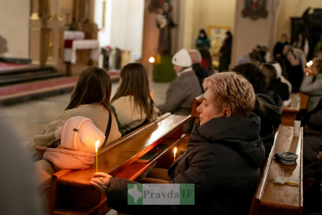 Люди моляться зі свічками в церкві