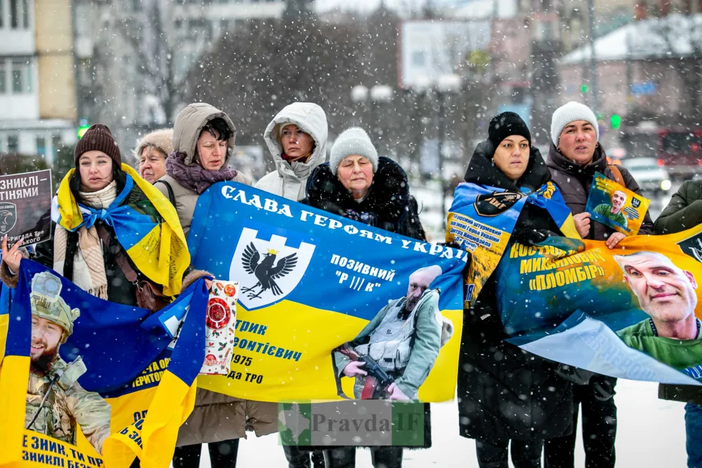 Люди тримають прапори та плакати героїв України