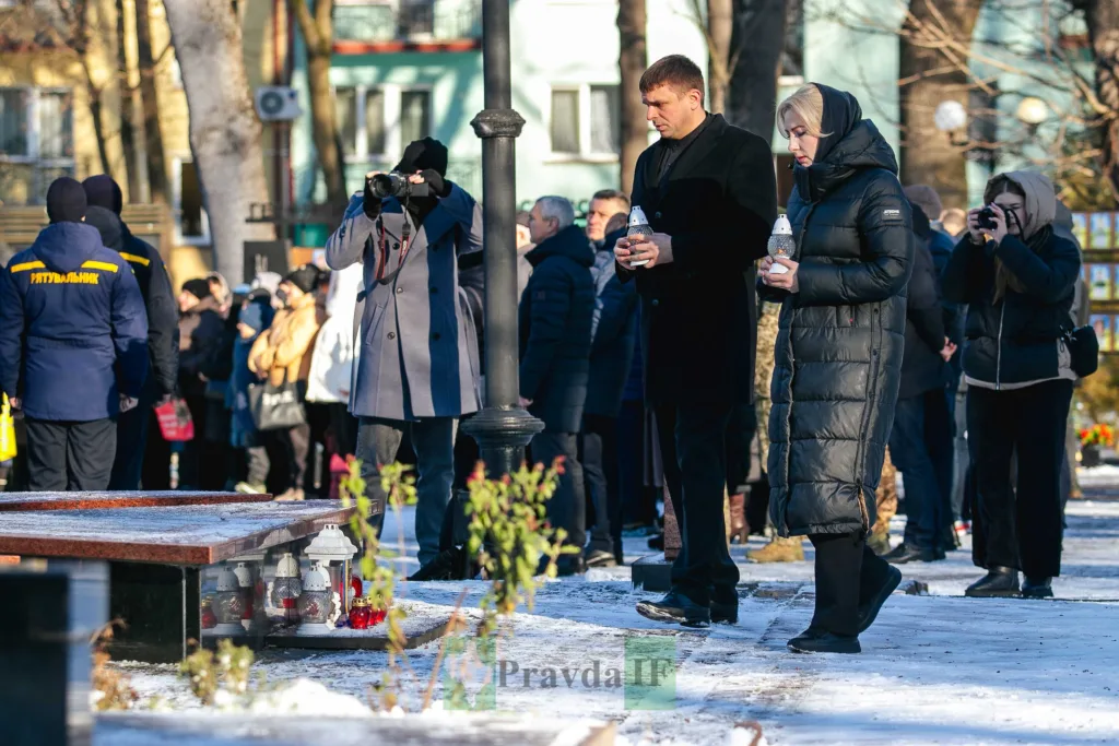 Люди вшановують пам'ять біля меморіалу взимку