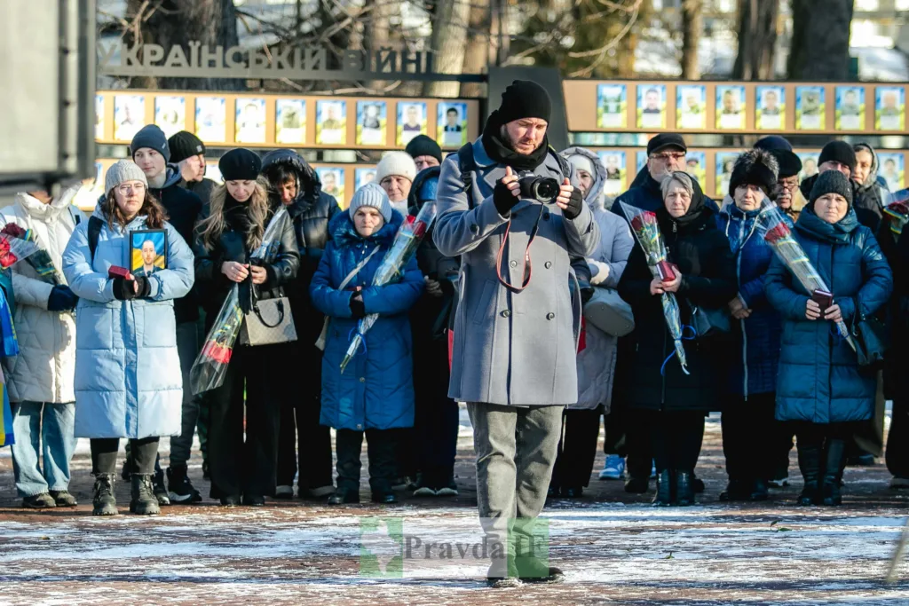 Люди з квітами на меморіальному заході взимку