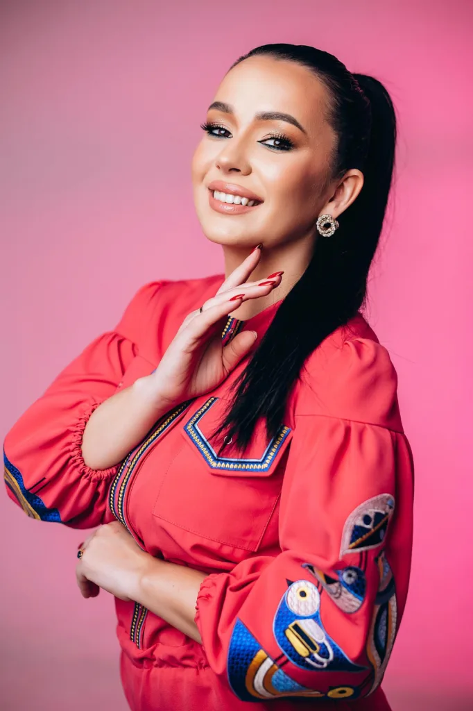 Жінка усміхається в рожевому вбранні на рожевому фоні