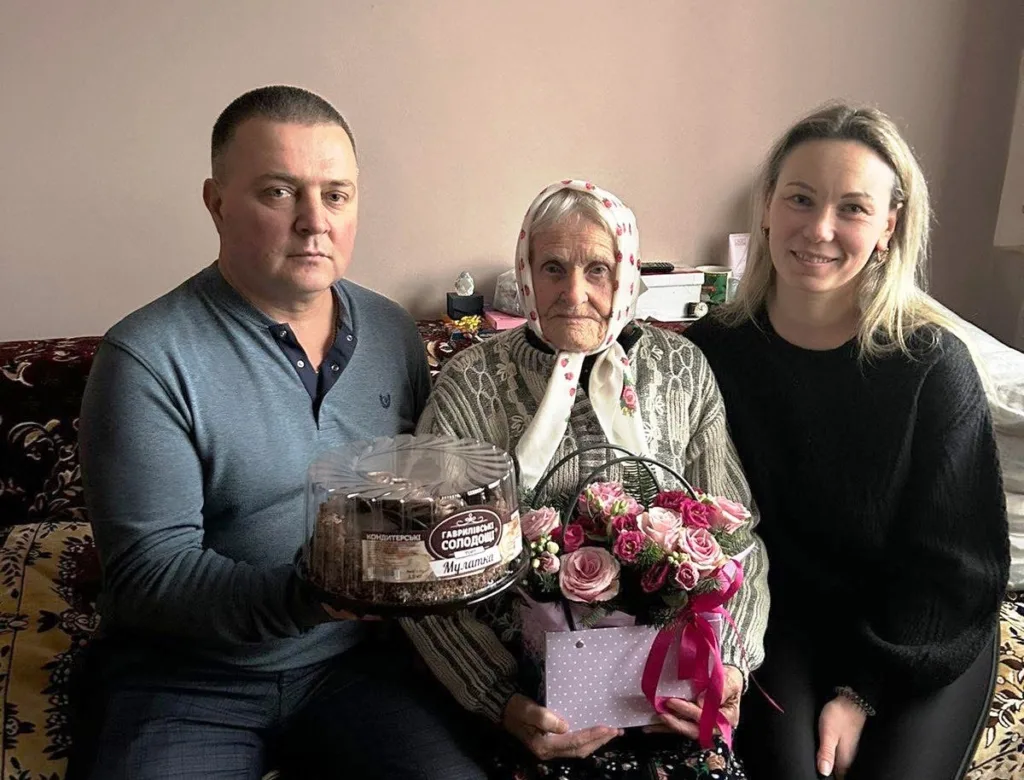 Родина святкує день народження бабусі з тортом і квітами