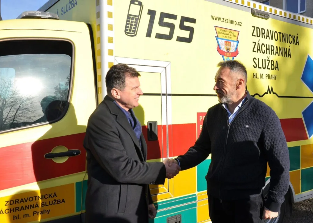 Двоє чоловіків тиснуть руки біля машини швидкої