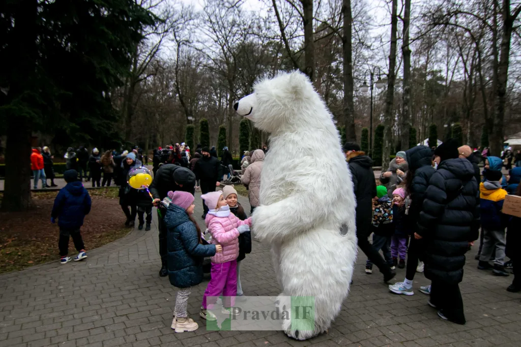 Діти вітаються з ведмедем у костюмі в парку