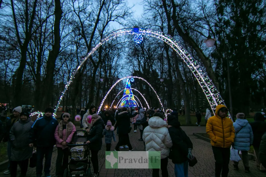 Люди гуляють під святковими вогнями в парку