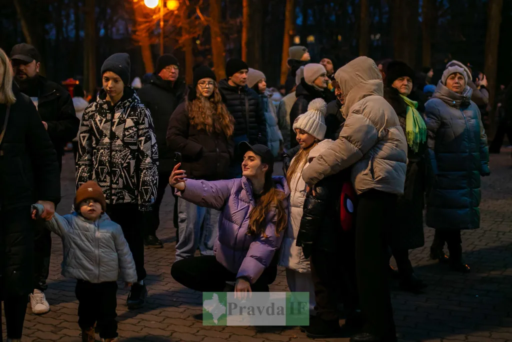 Люди роблять селфі на вечірньому святі в парку