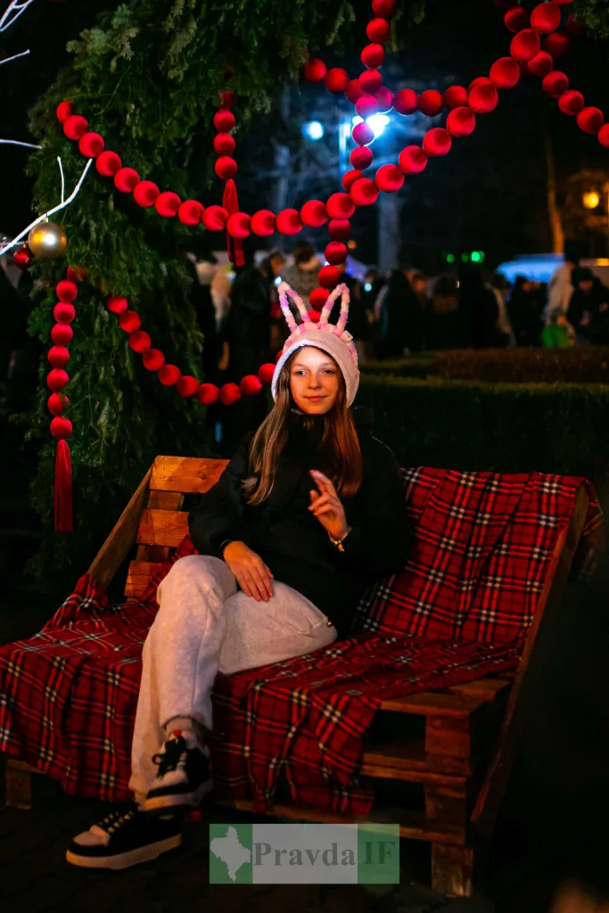 Дівчина у вушках сидить на святковій лавці