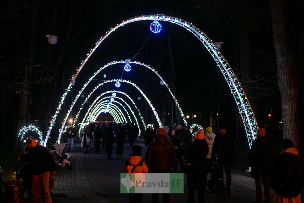 Нічна алея з різдвяними вогнями та людьми