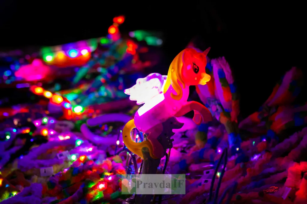 Іграшковий єдиноріг серед кольорових неонових вогнів
