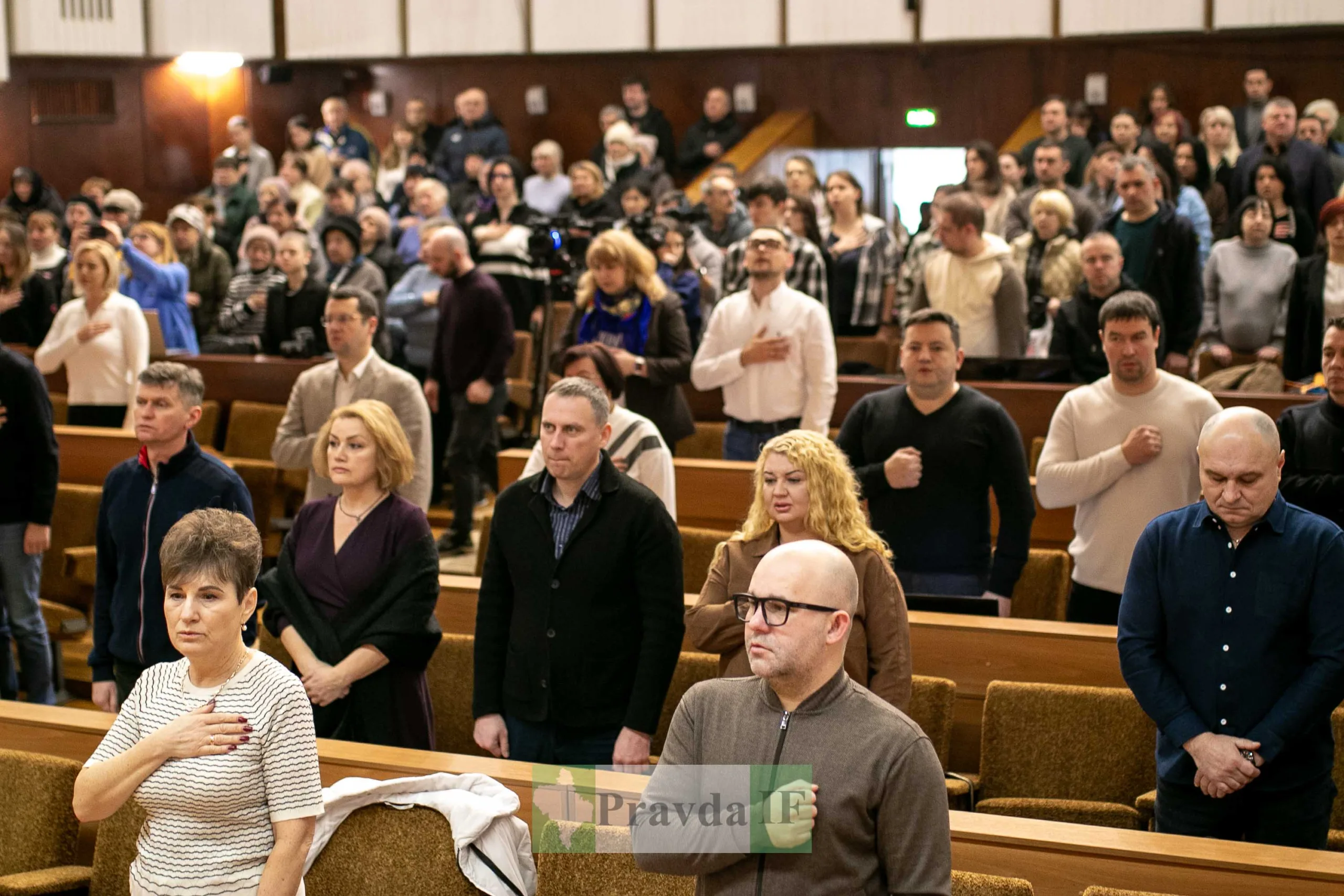 Люди стоять у залі під час урочистого заходу