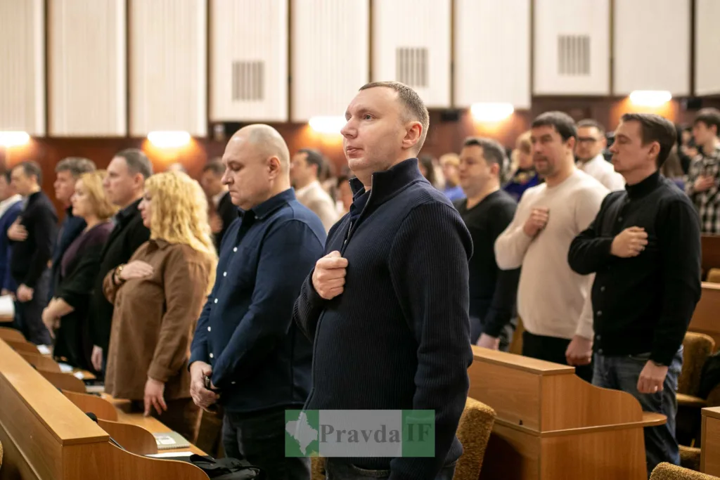 Люди стоять у залі з рукою на серці