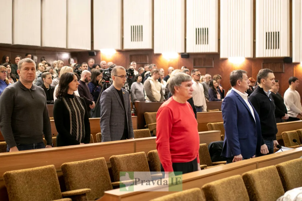 Люди стоять у залі під час офіційного засідання