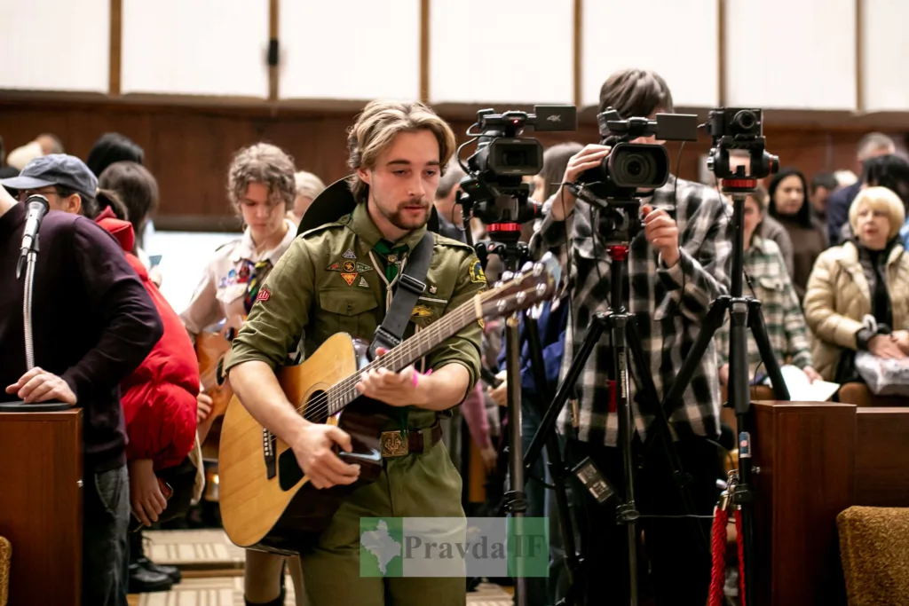 Скаут грає на гітарі перед камерами