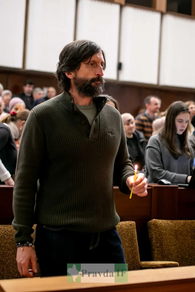 Чоловік тримає запалену свічку під час церемонії