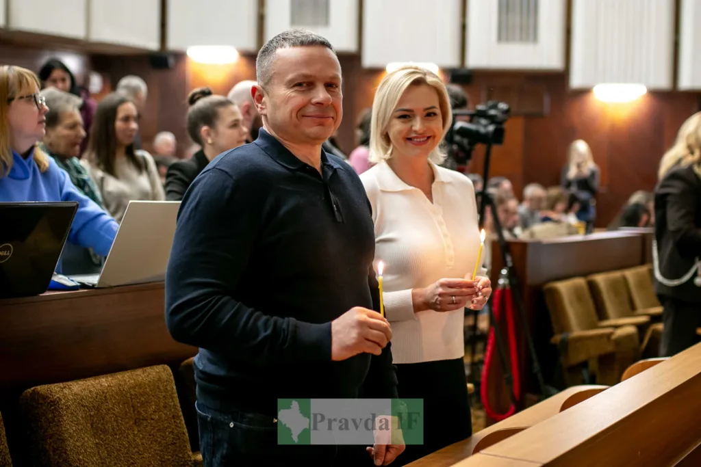 Люди з запаленими свічками в залі засідань