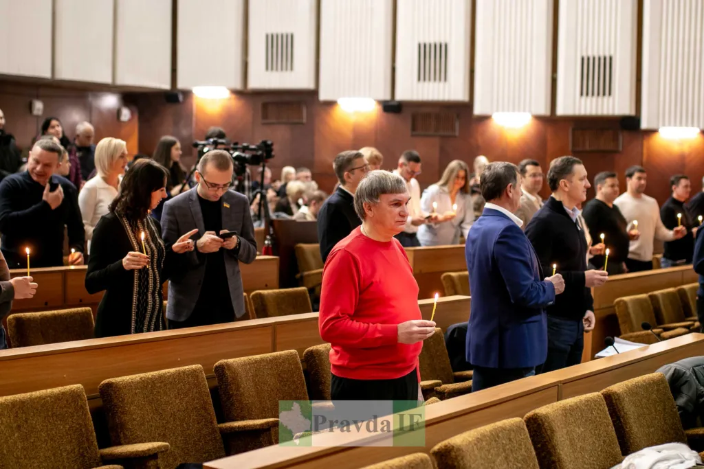 Люди стоять у залі з запаленими свічками