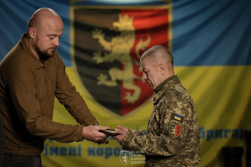 Військовий отримує нагороду перед українським прапором