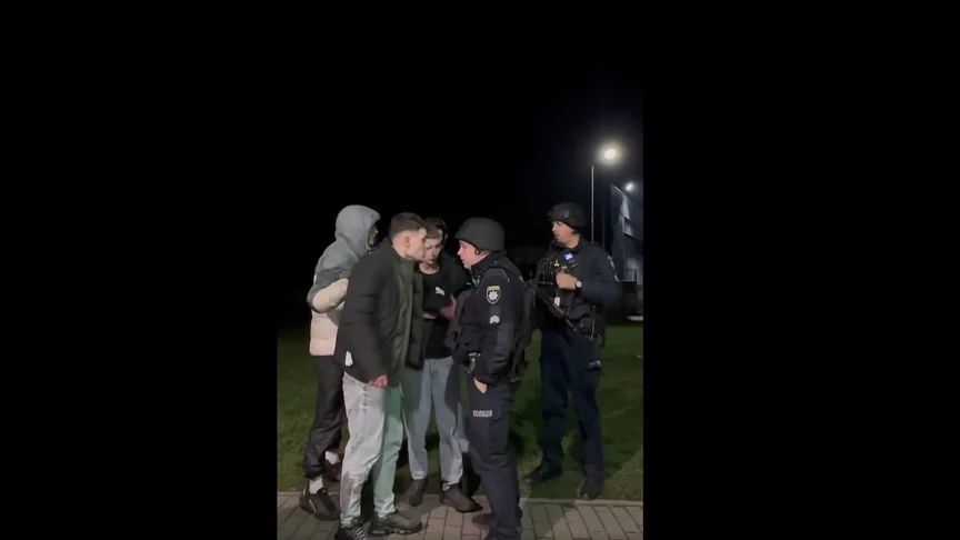 Поліція спілкується з групою чоловіків уночі