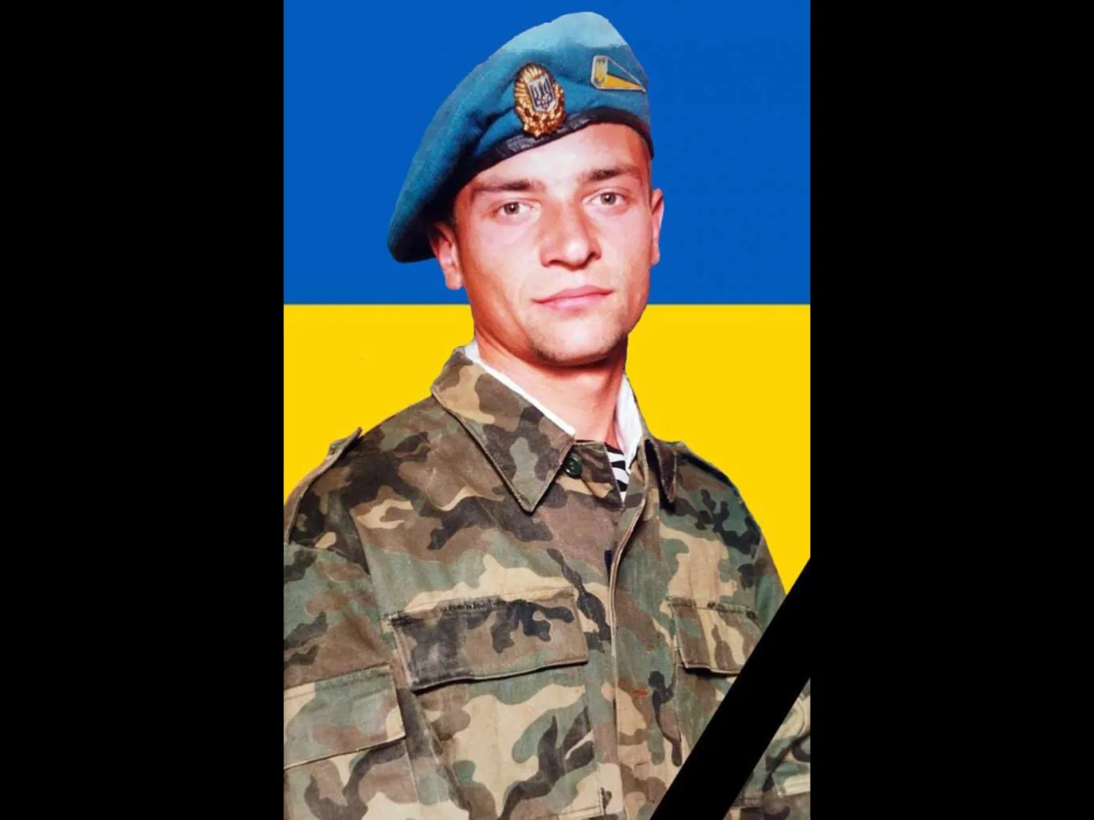 Український військовий у формі на тлі прапора