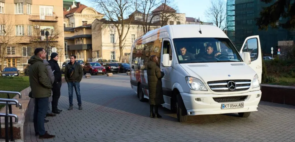 Люди біля білого мікроавтобуса на міській вулиці