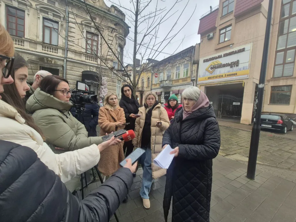Жінка дає інтерв’ю журналістам на вулиці міста