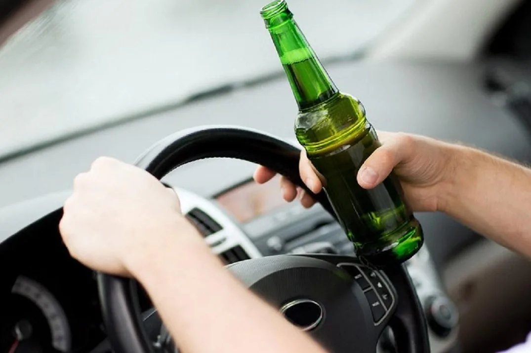 Водій тримає пиво за кермом автомобіля