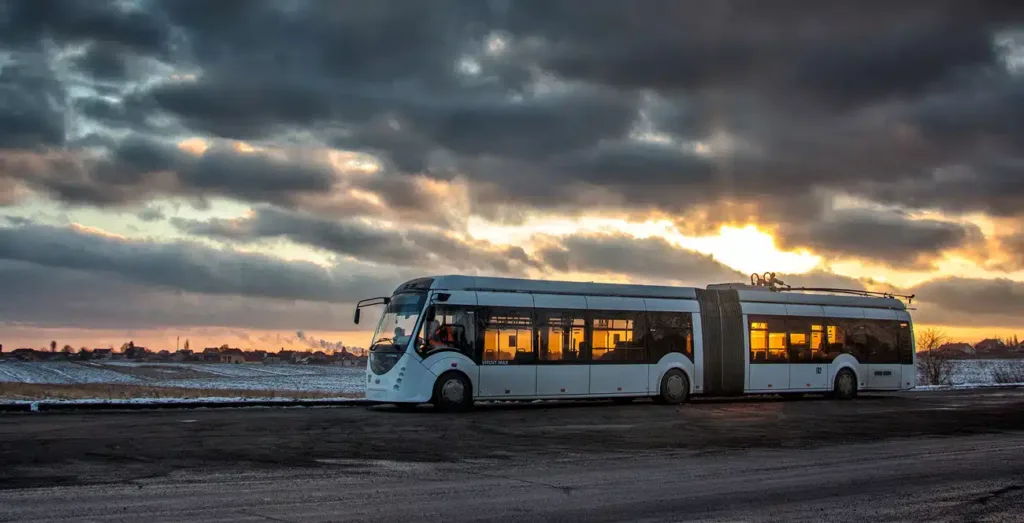 Сучасний тролейбус на дорозі під заходом сонця