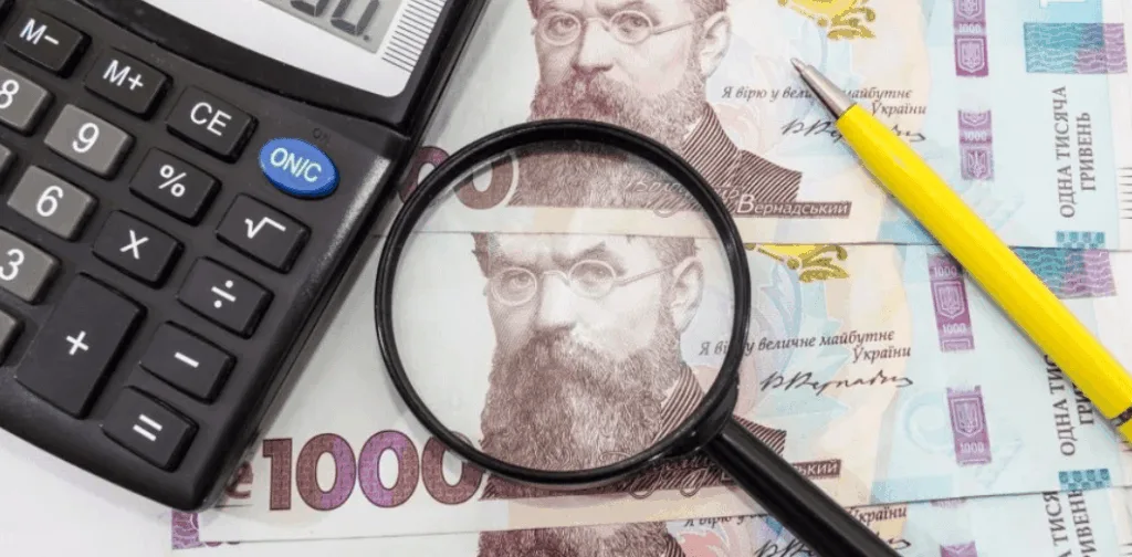Калькулятор, лупа і українські гривні на столі