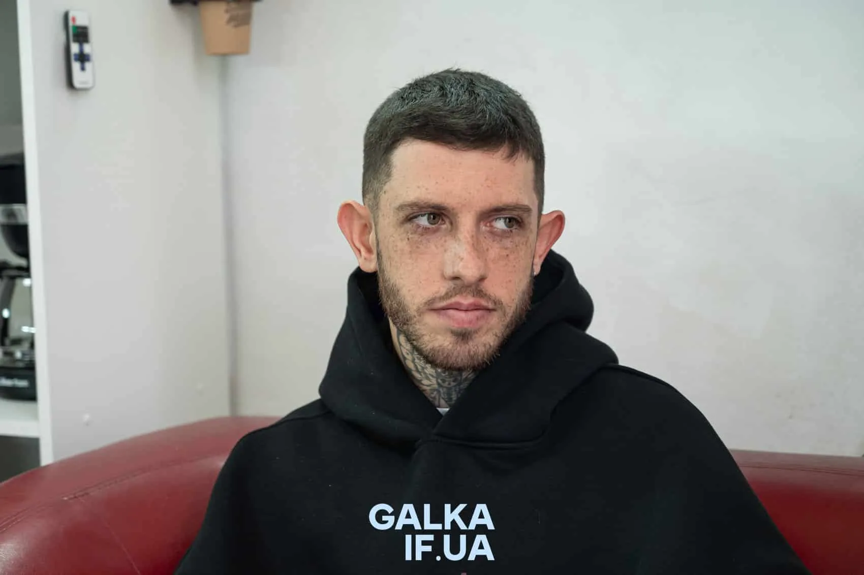 Чоловік у чорній худі сидить на дивані