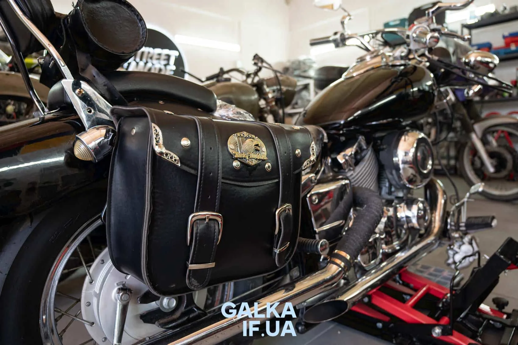 Чорний мотоцикл з шкіряною кофрою у гаражі