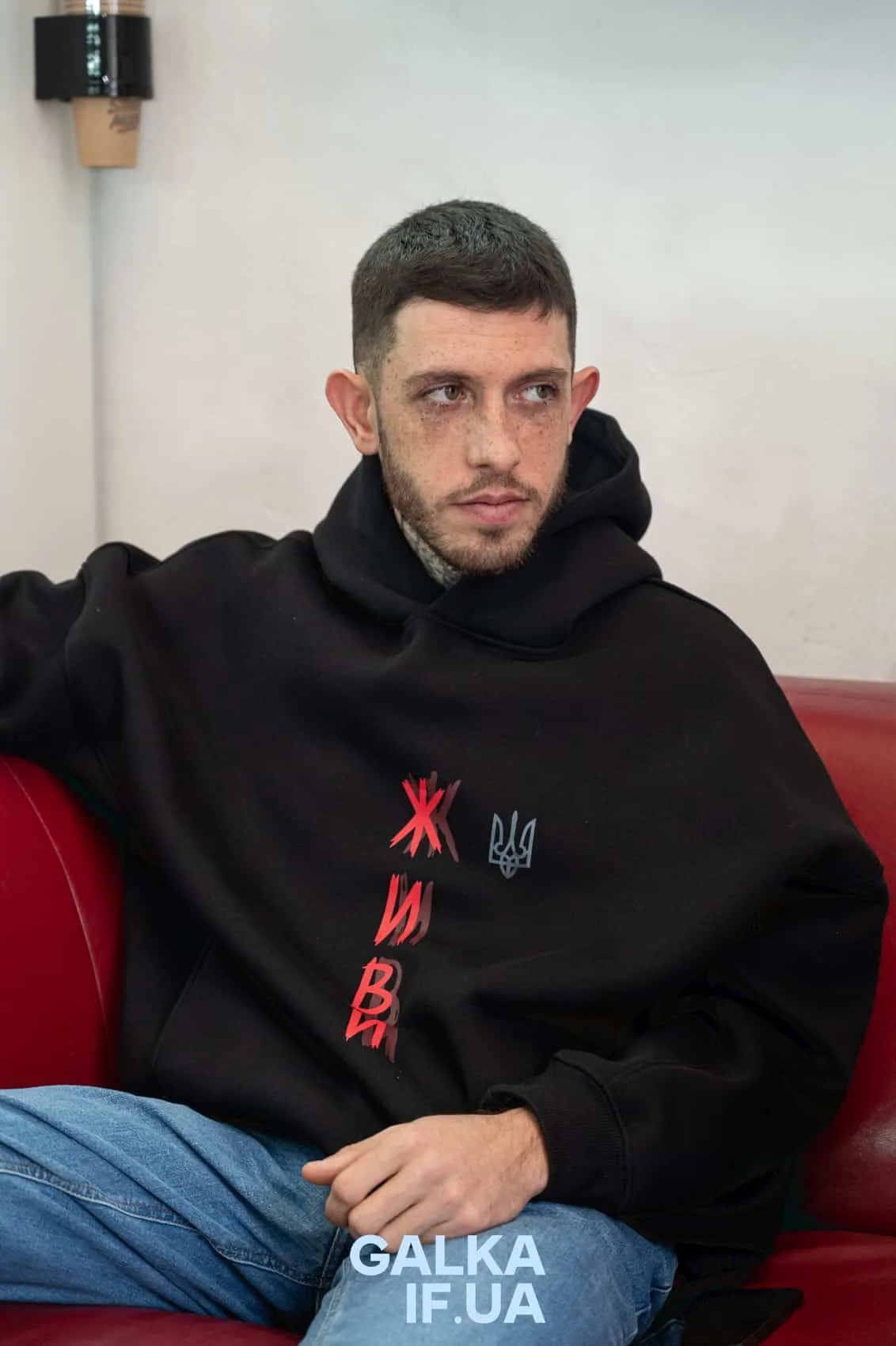 Чоловік у чорній худі з написом Живи