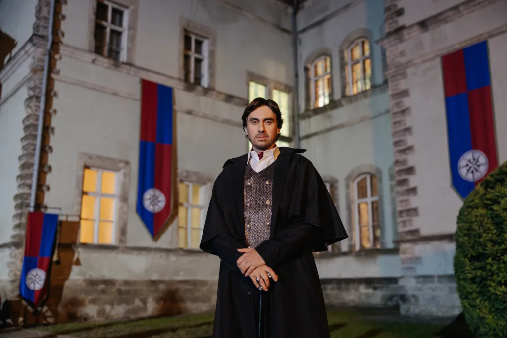 Чоловік у плащі перед старовинним замком