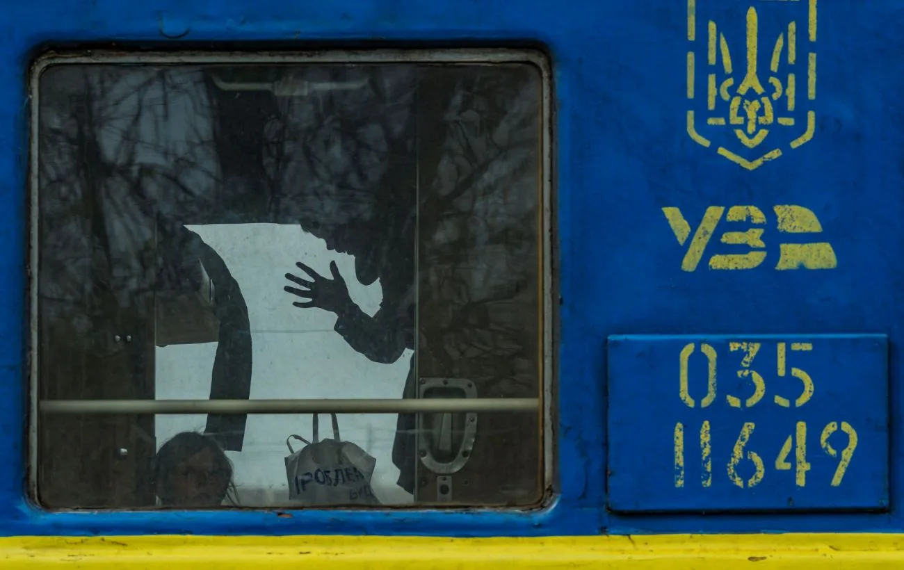 Люди у вікні синьо-жовтого українського потяга