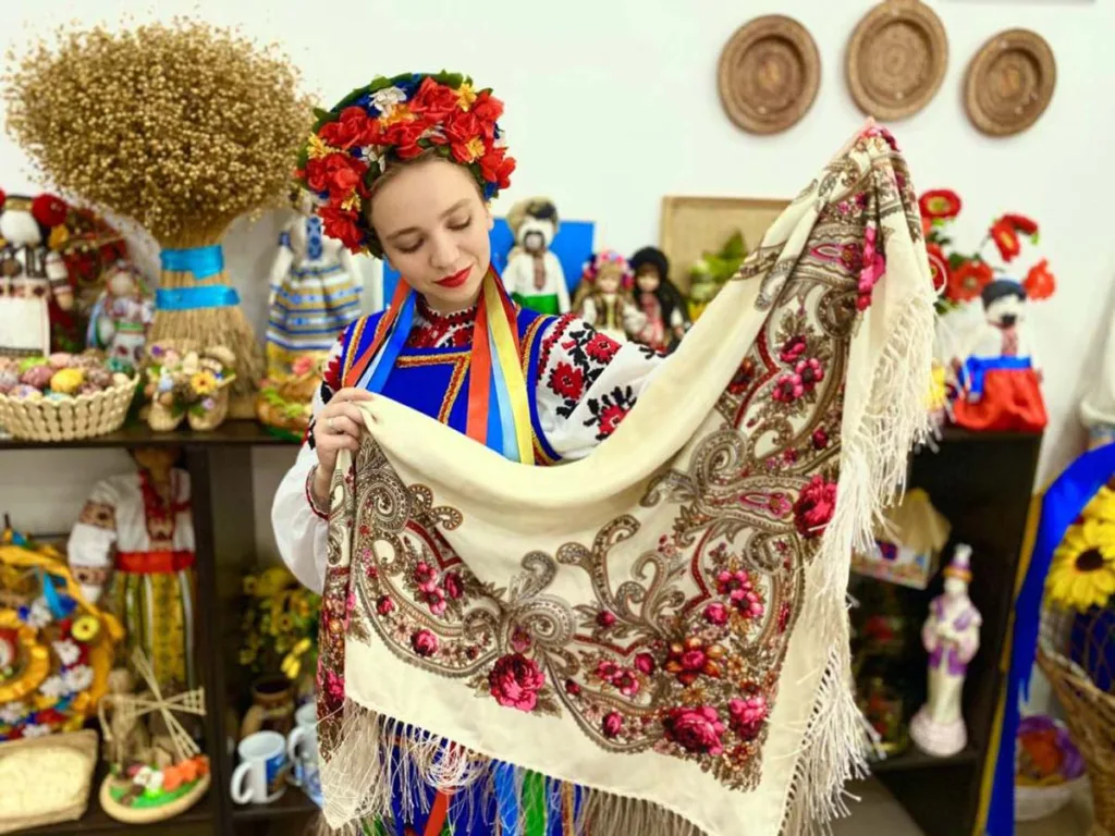 Дівчина у вишиванці тримає українську хустку