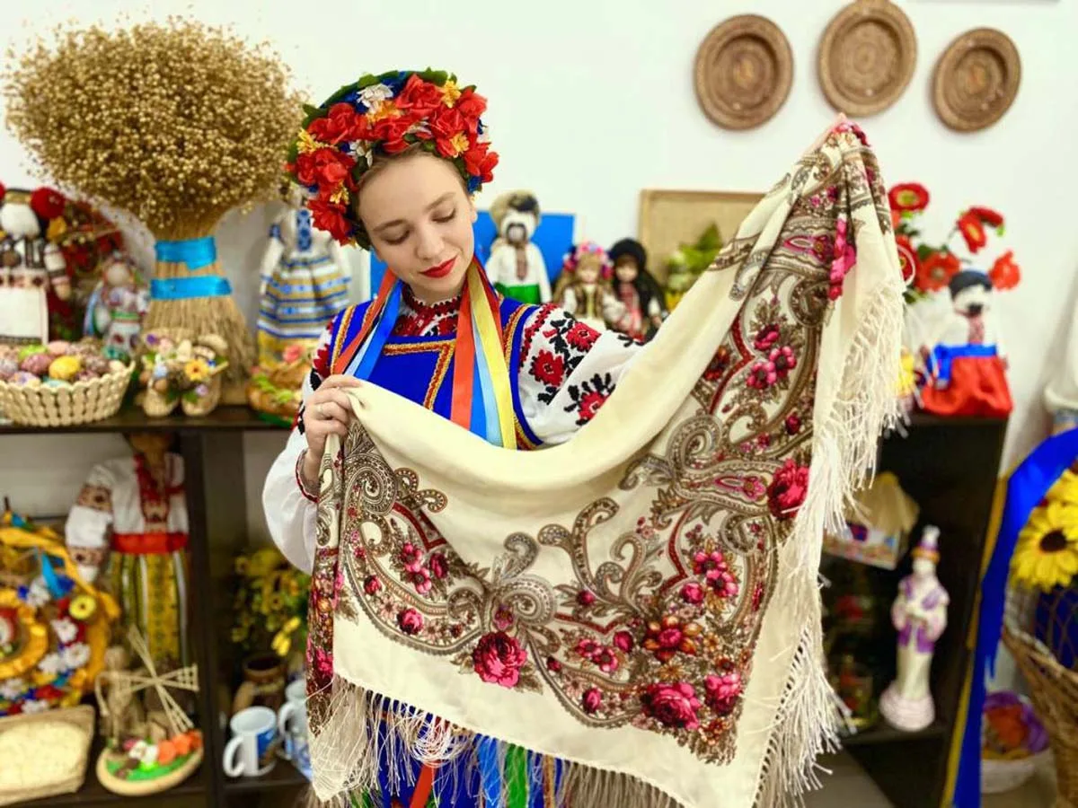 Дівчина у вишиванці тримає українську хустку