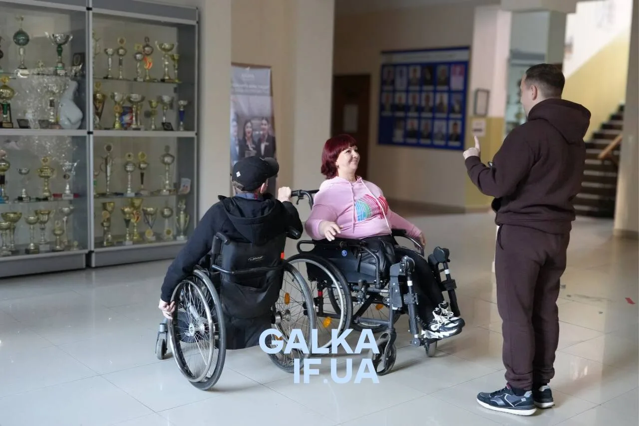 Люди на візках спілкуються у шкільному холі