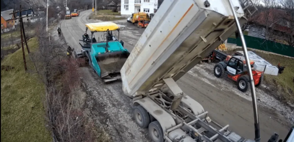 Ремонт дороги з асфальтоукладальником і вантажівкою