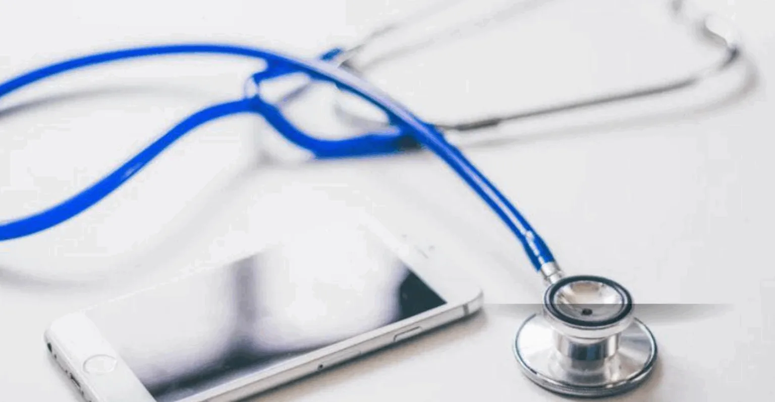 Смартфон і стетоскоп на білому столі