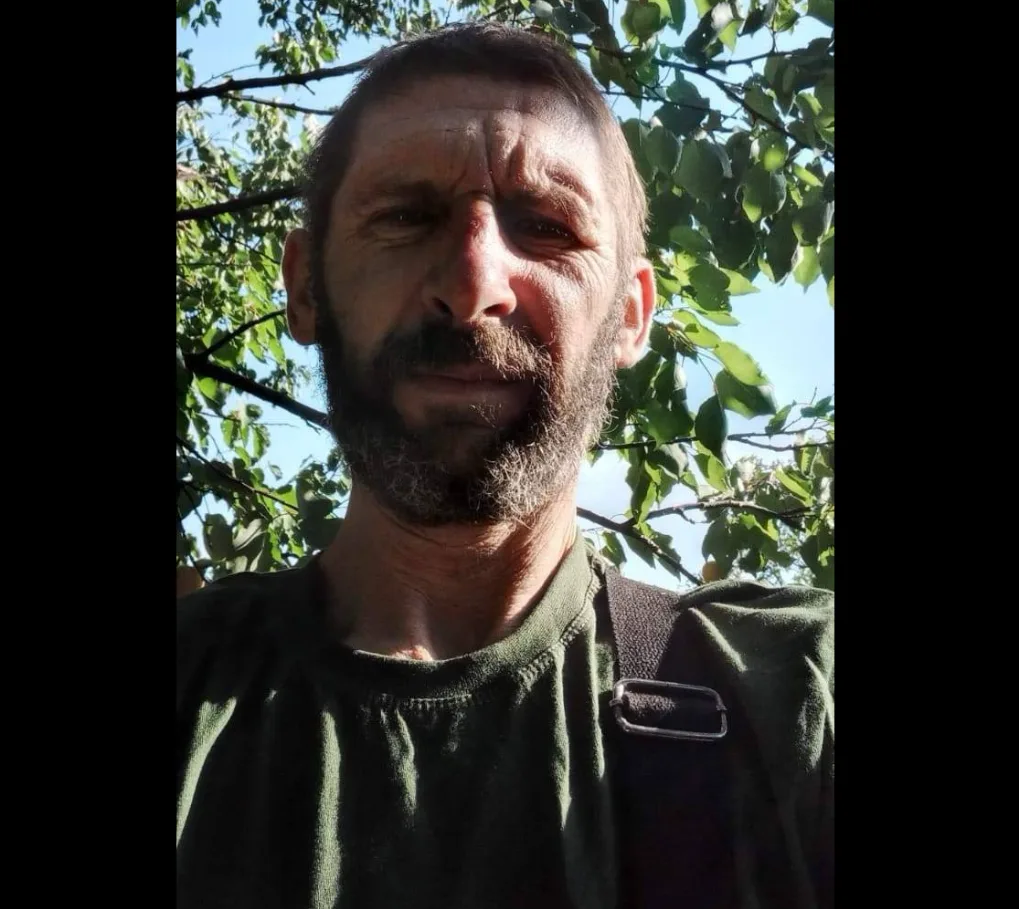 Чоловік на вулиці серед зеленого листя