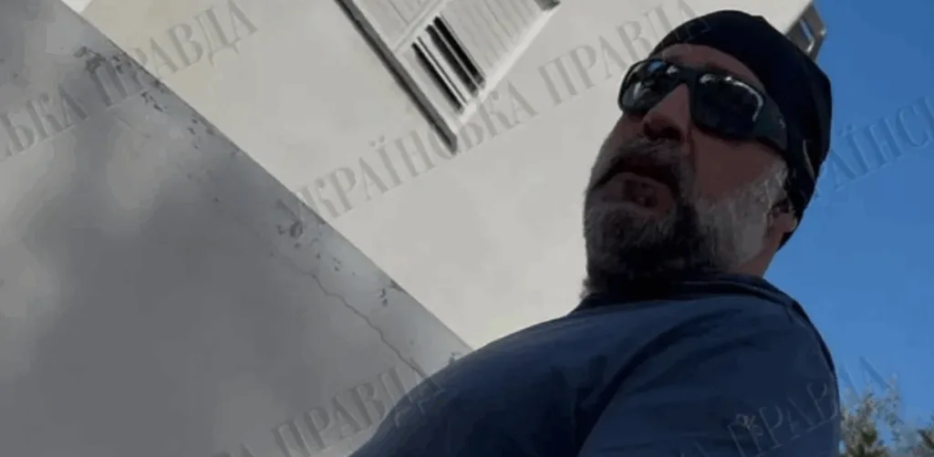 Чоловік у сонцезахисних окулярах біля будівлі