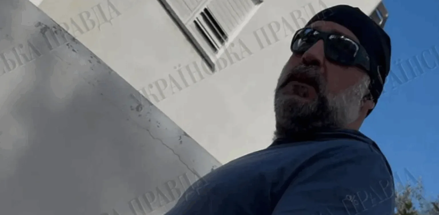 Чоловік у сонцезахисних окулярах біля будівлі