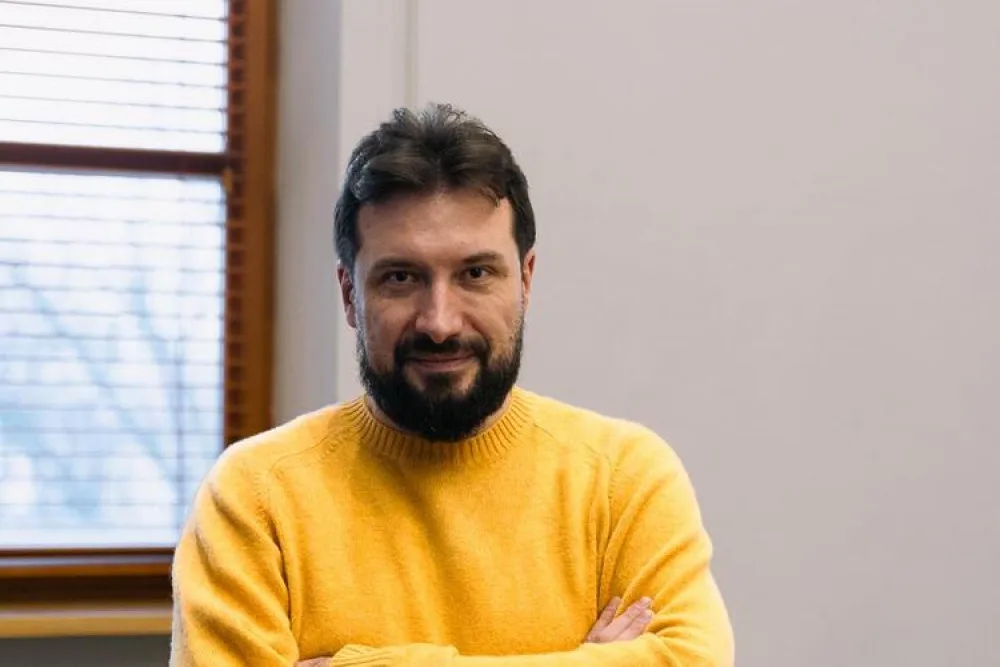 Чоловік у жовтому светрі стоїть у кімнаті