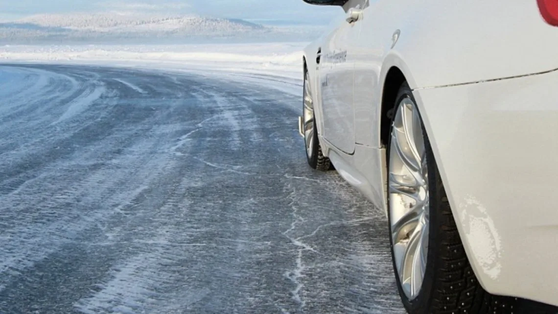 Білий автомобіль їде по крижаній дорозі